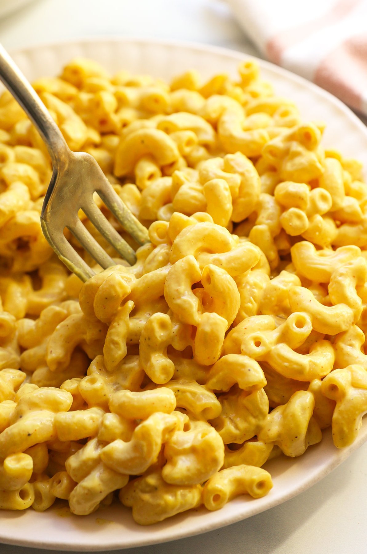 vegan mac and cheese served on a white plate with a fork. 