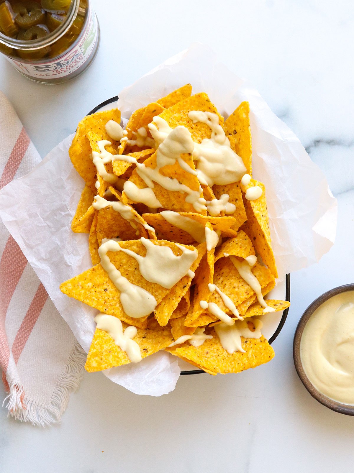 vegan nacho cheese sauce drizzled on yellow corn tortilla chips.