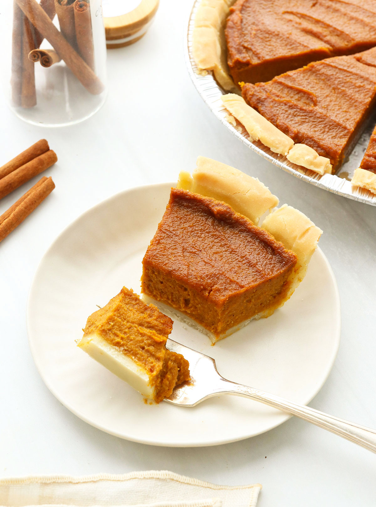 Vegan Pumpkin pie slice cut with a fork on a white plate.