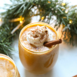 vegan eggnog in a gold rimmed glass with garland in background.
