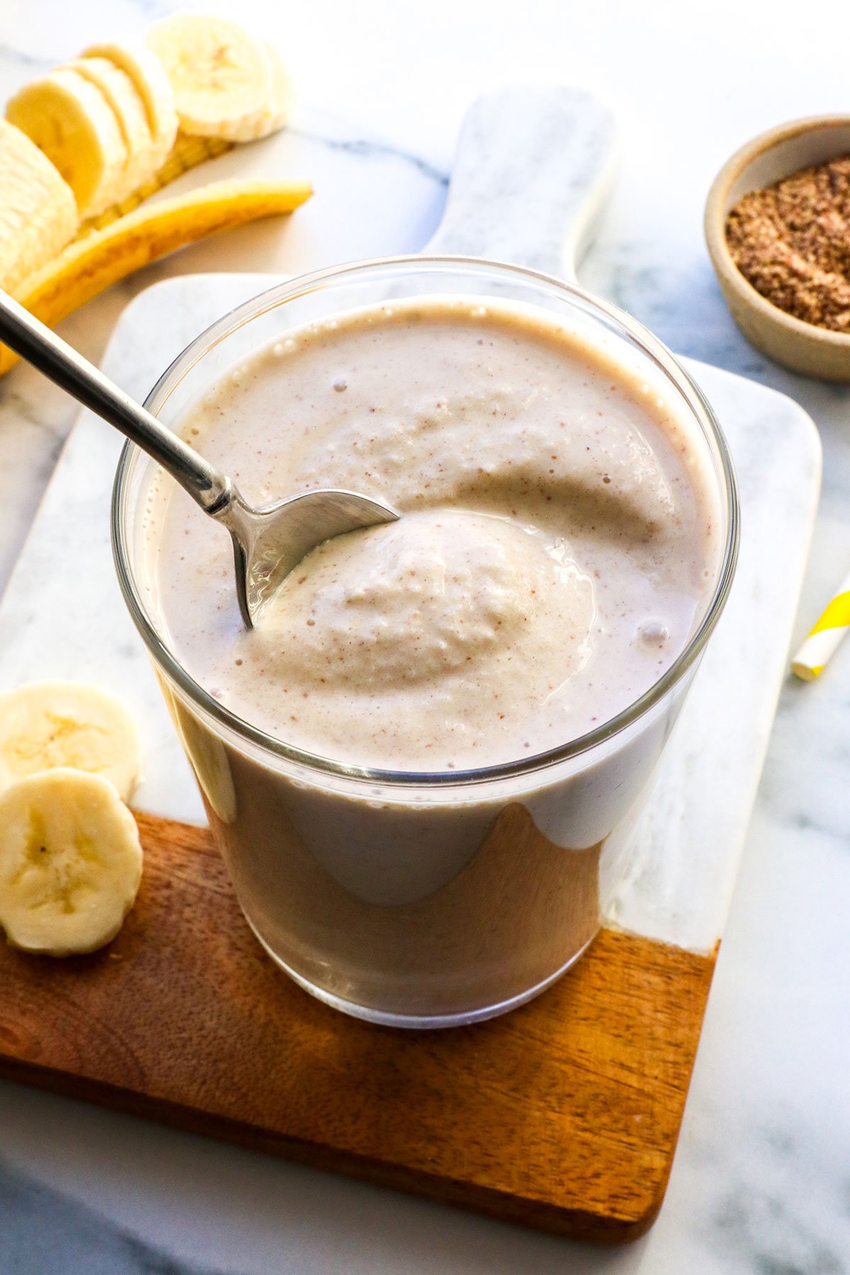 banana peanut butter smoothie stirred with a spoon to show the ice cream texture.