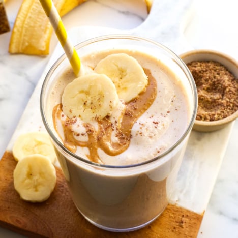 smoothie in a glass topped with peanut butter and banana slices.