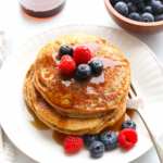 protein pancakes served on a plate with fruit.