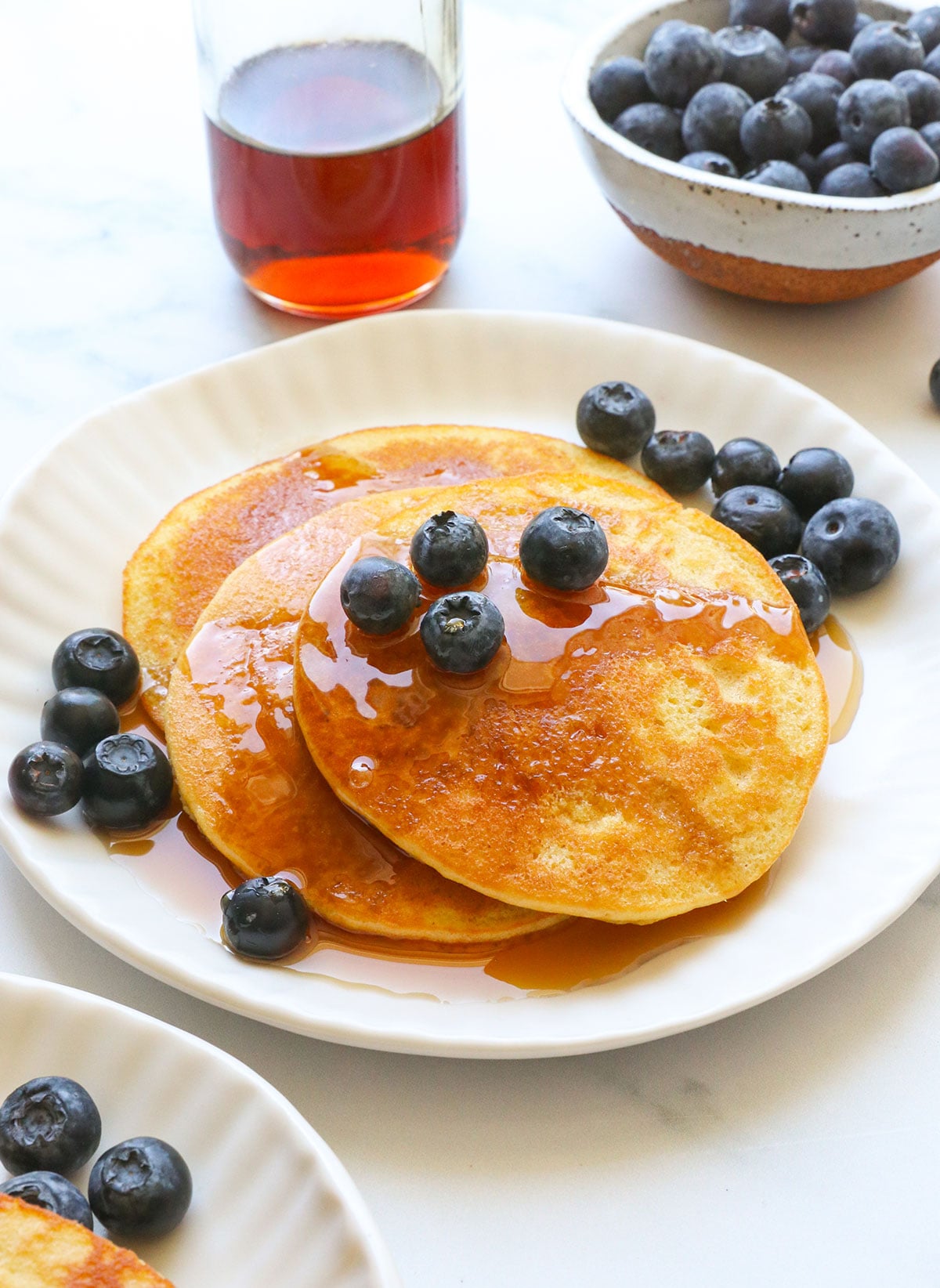 almond flour pancakes stacked on a plate with fresh blueberries.
