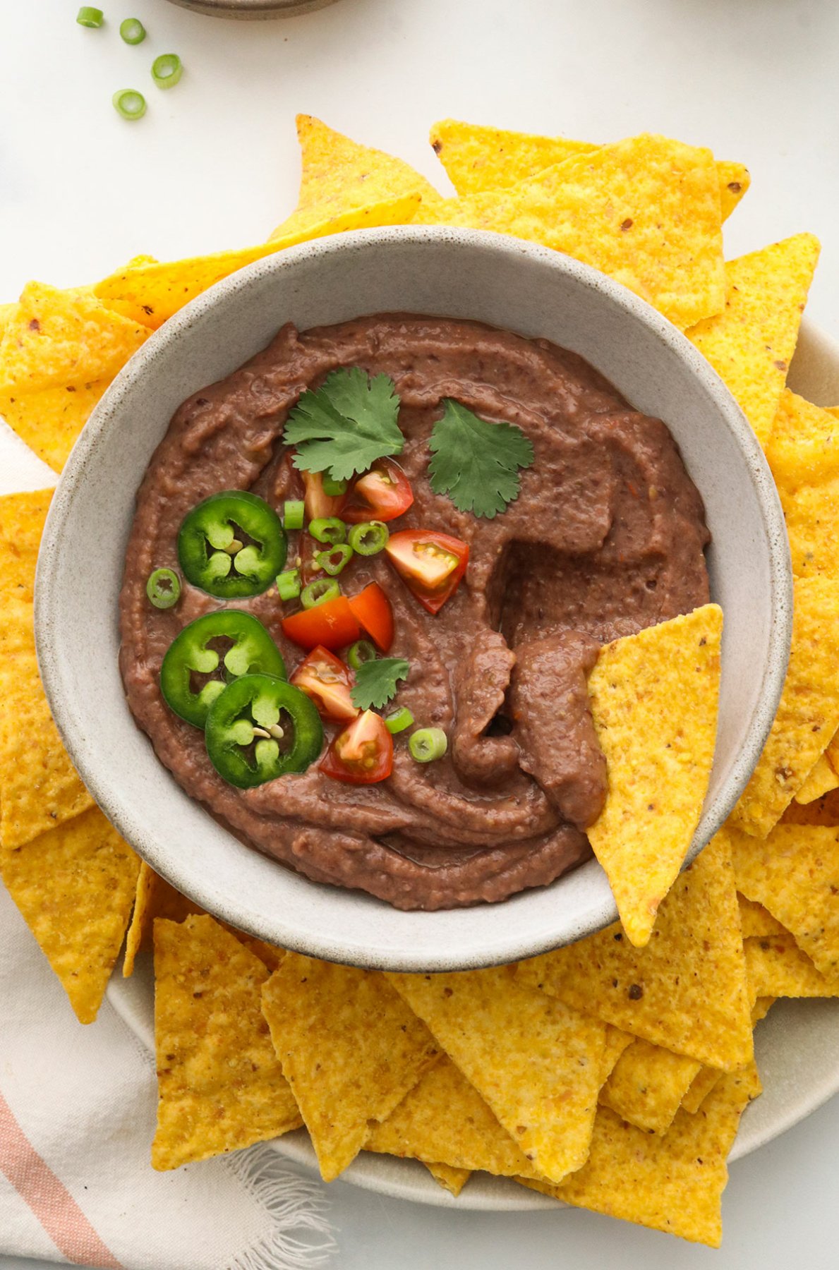 black bean dip topped with tomatoes and cilantro with tortilla chips for dipping.