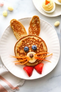 Pancakes decorated like a bunny with carrot whiskers.