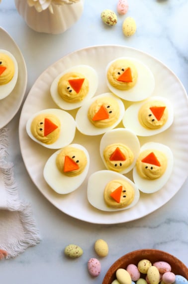 Easter deviled eggs served on a white plate overhead.
