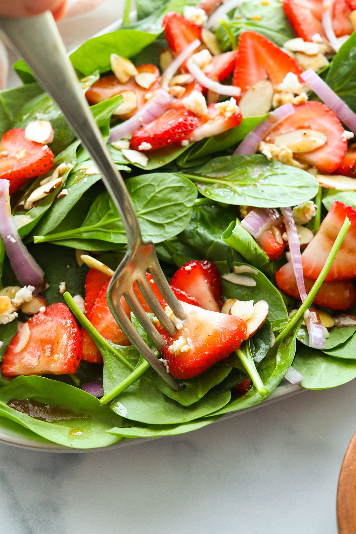 fork stuck into spinach strawberry salad.
