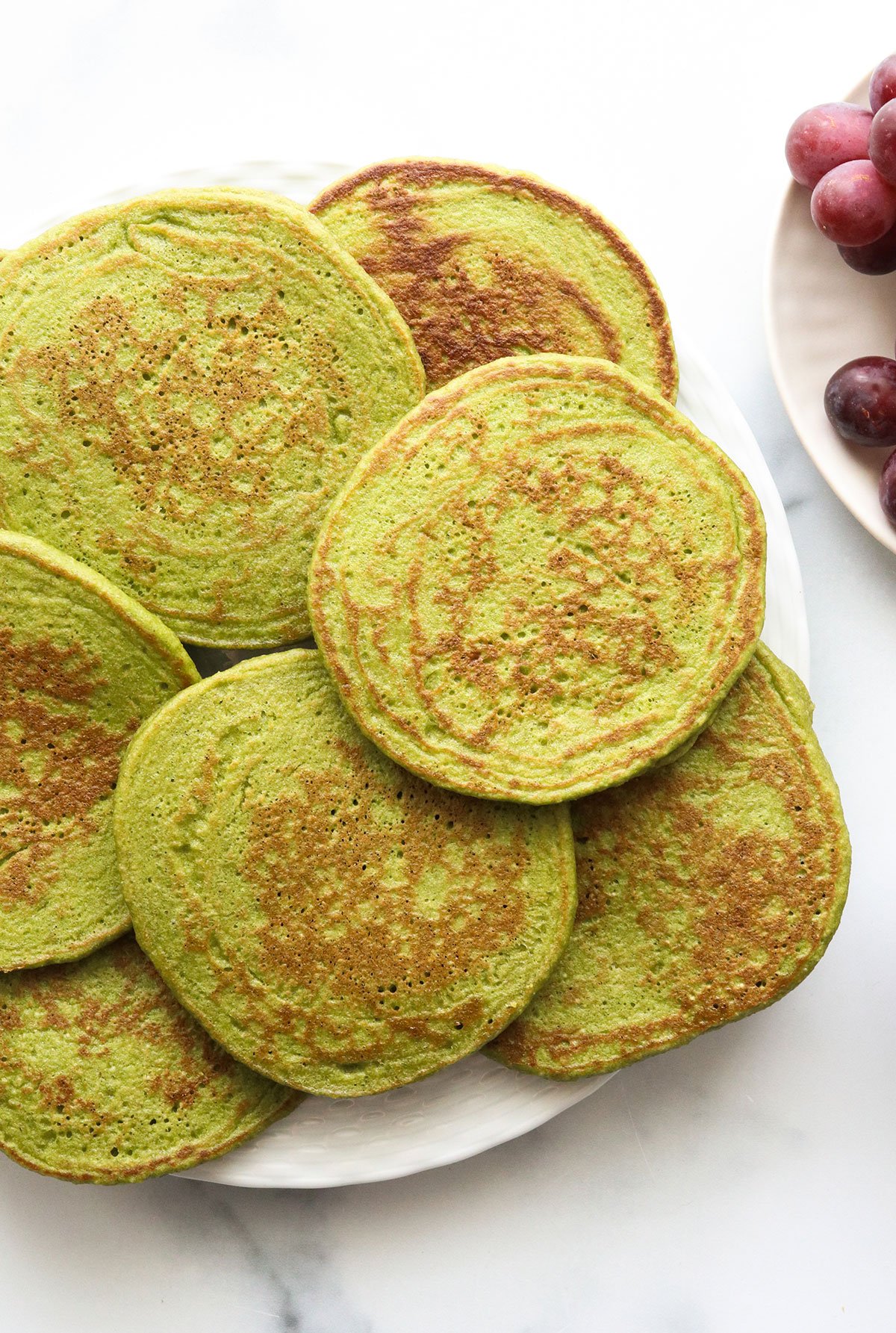 spinach pancakes arranged on a white plate overhead.