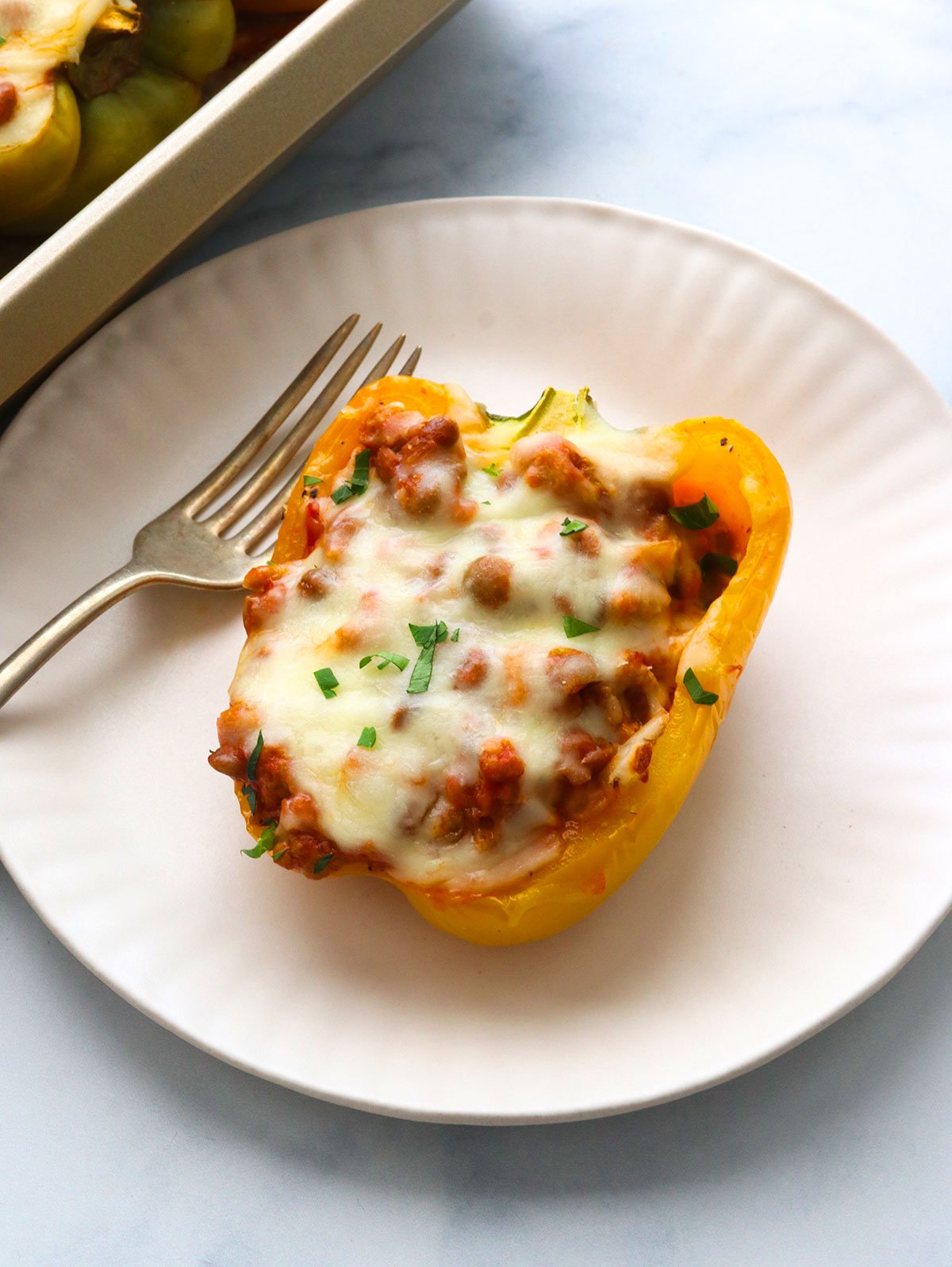 ground turkey stuffed pepper on a white plate with a fork. 