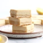 vegan lemon bars stacked on a white plate.