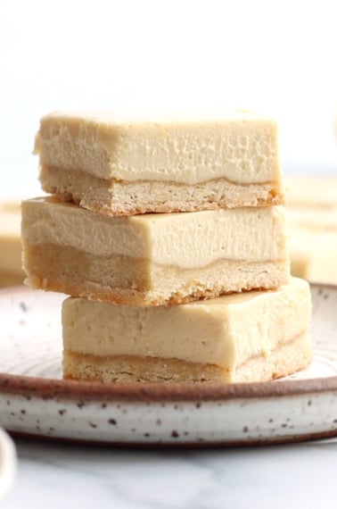 vegan lemon bars stacked on a white plate.
