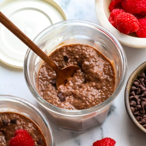 chocolate chia pudding in two glass jars with raspberries.