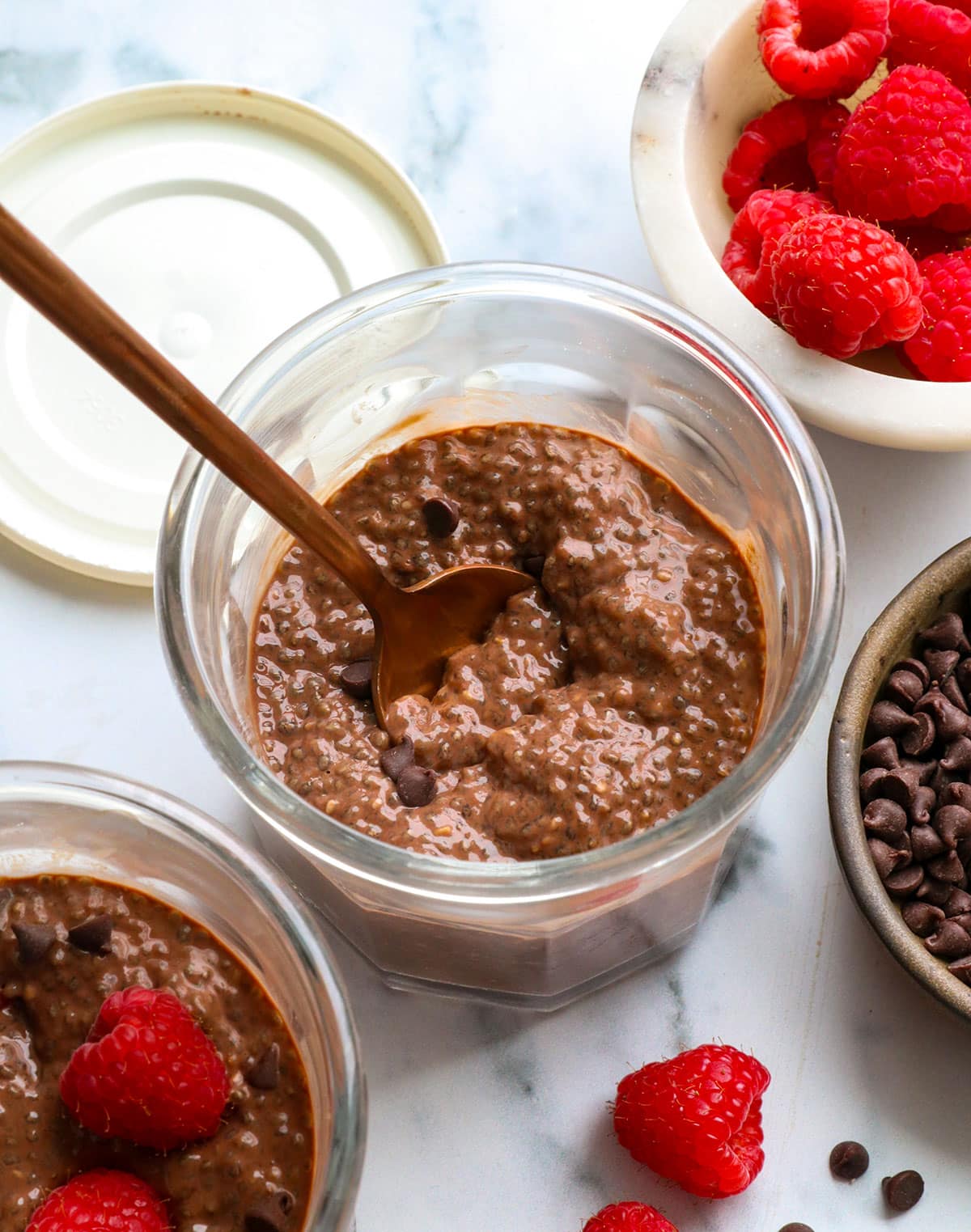 chocolate chia pudding in two glass jars with raspberries.