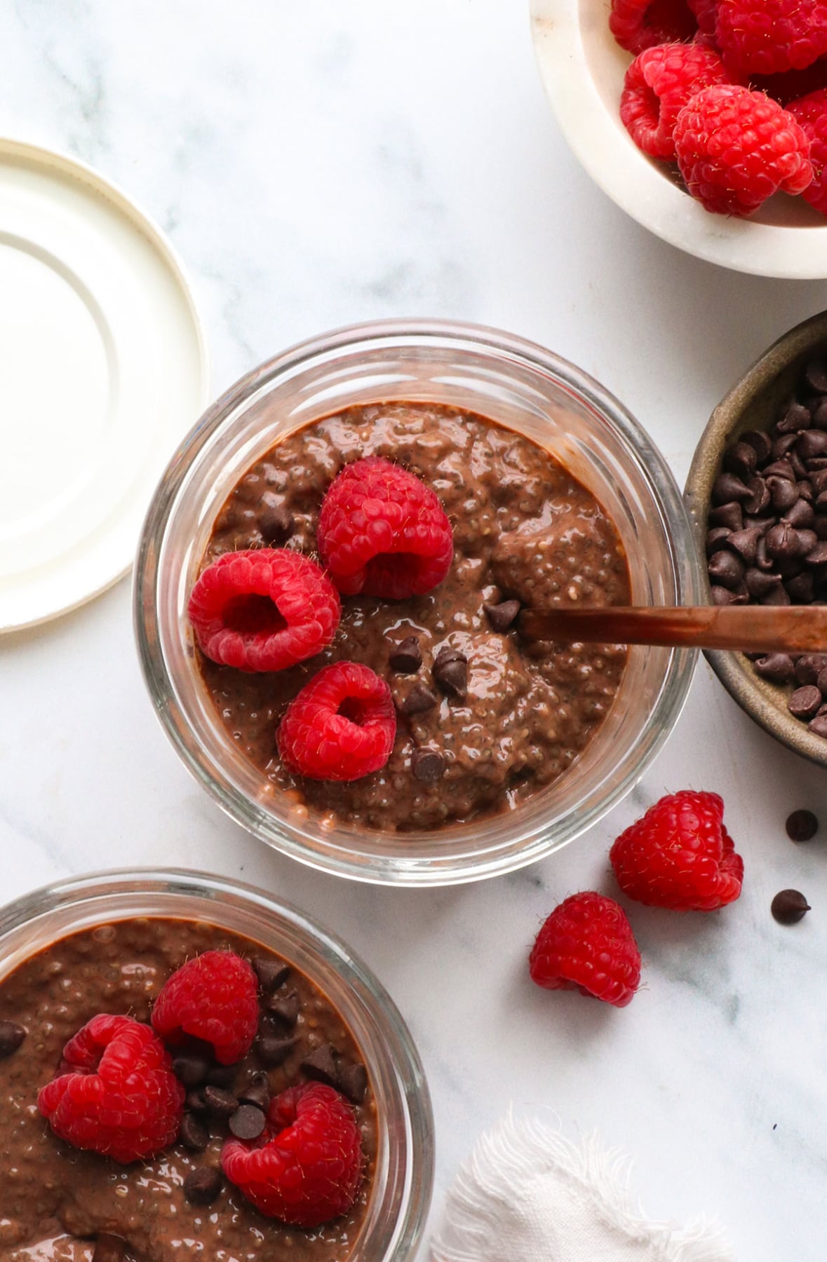 chocolate chia pudding served overhead with raspberries and mini chocolate chips. 