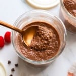 chocolate chia pudding lifted on a spoon over the serving jar.