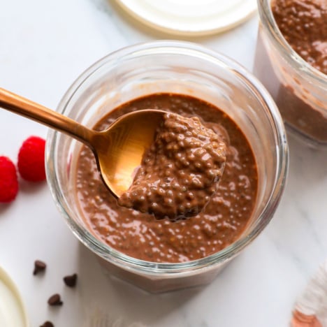 chocolate chia pudding lifted on a spoon over the serving jar.