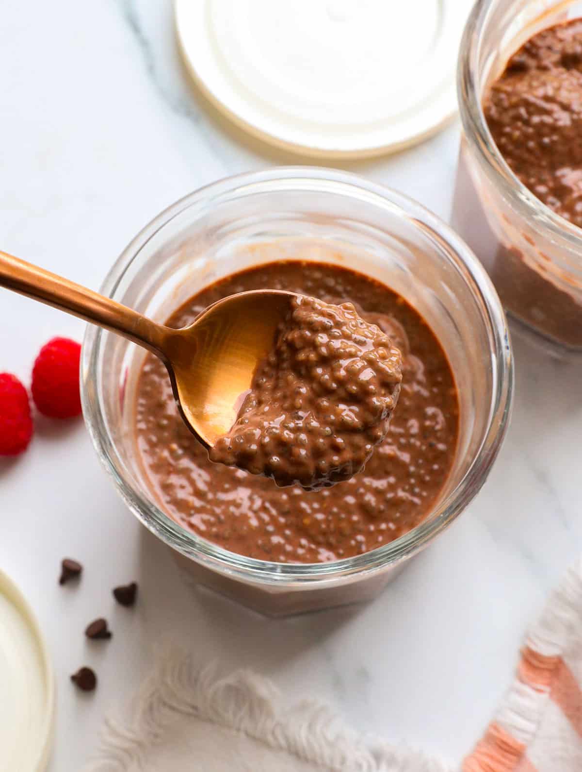chocolate chia pudding lifted on a spoon over the serving jar. 