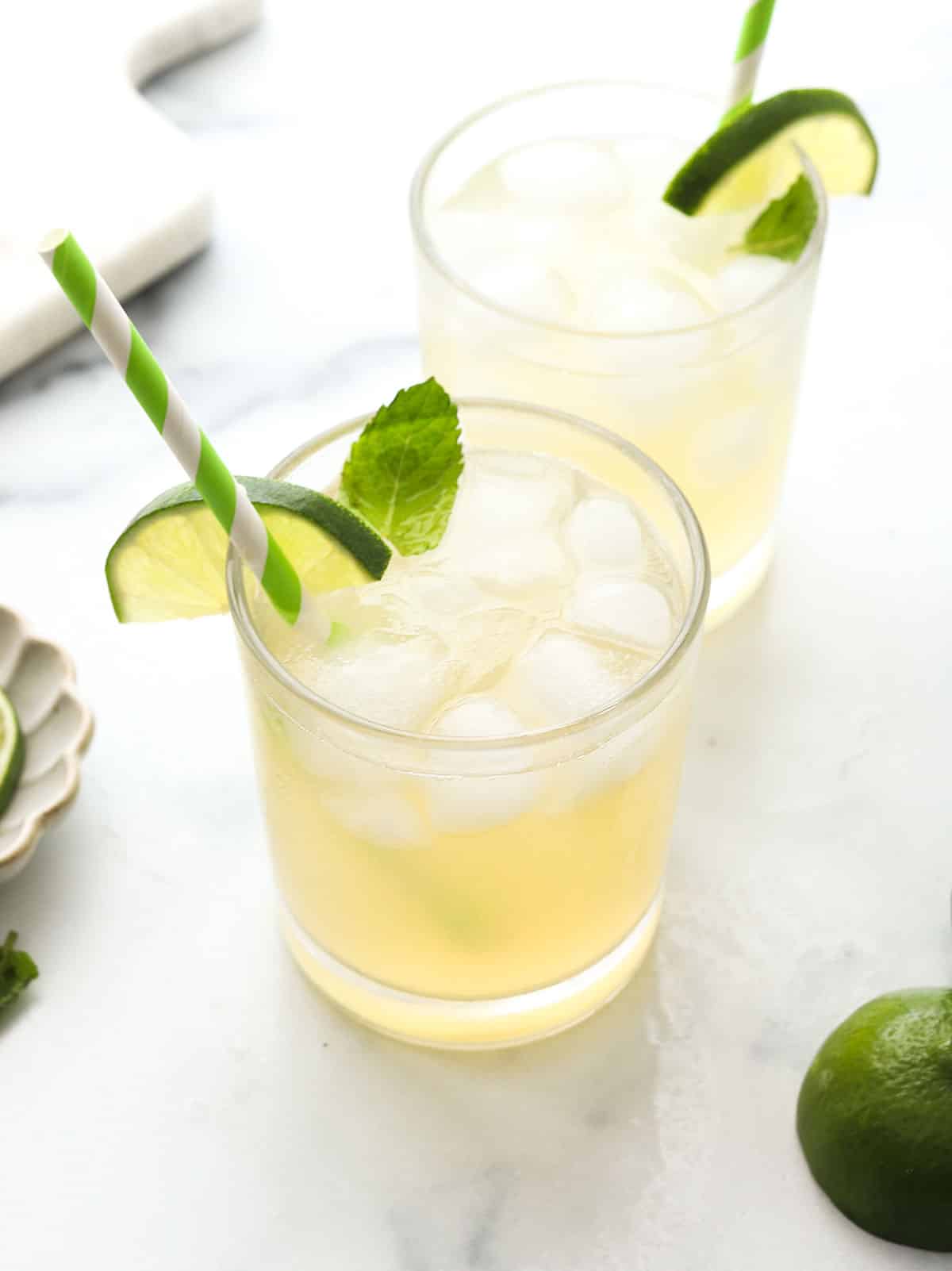 mojito mocktail in two glasses with lime slice as a garnish.