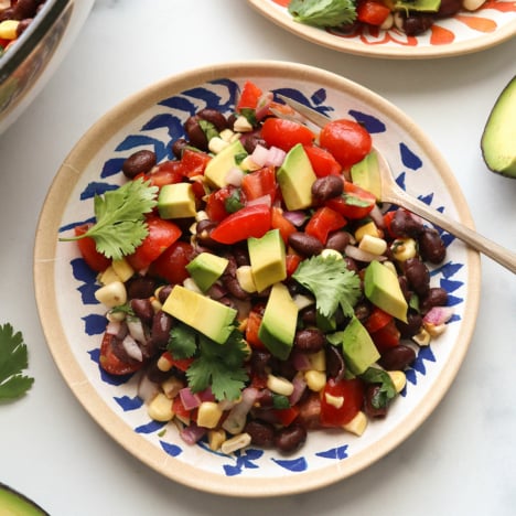 black bean salad on a colorful plate and topped with avocado.