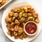 oven roasted potatoes on a white plate with a side of ketchup.