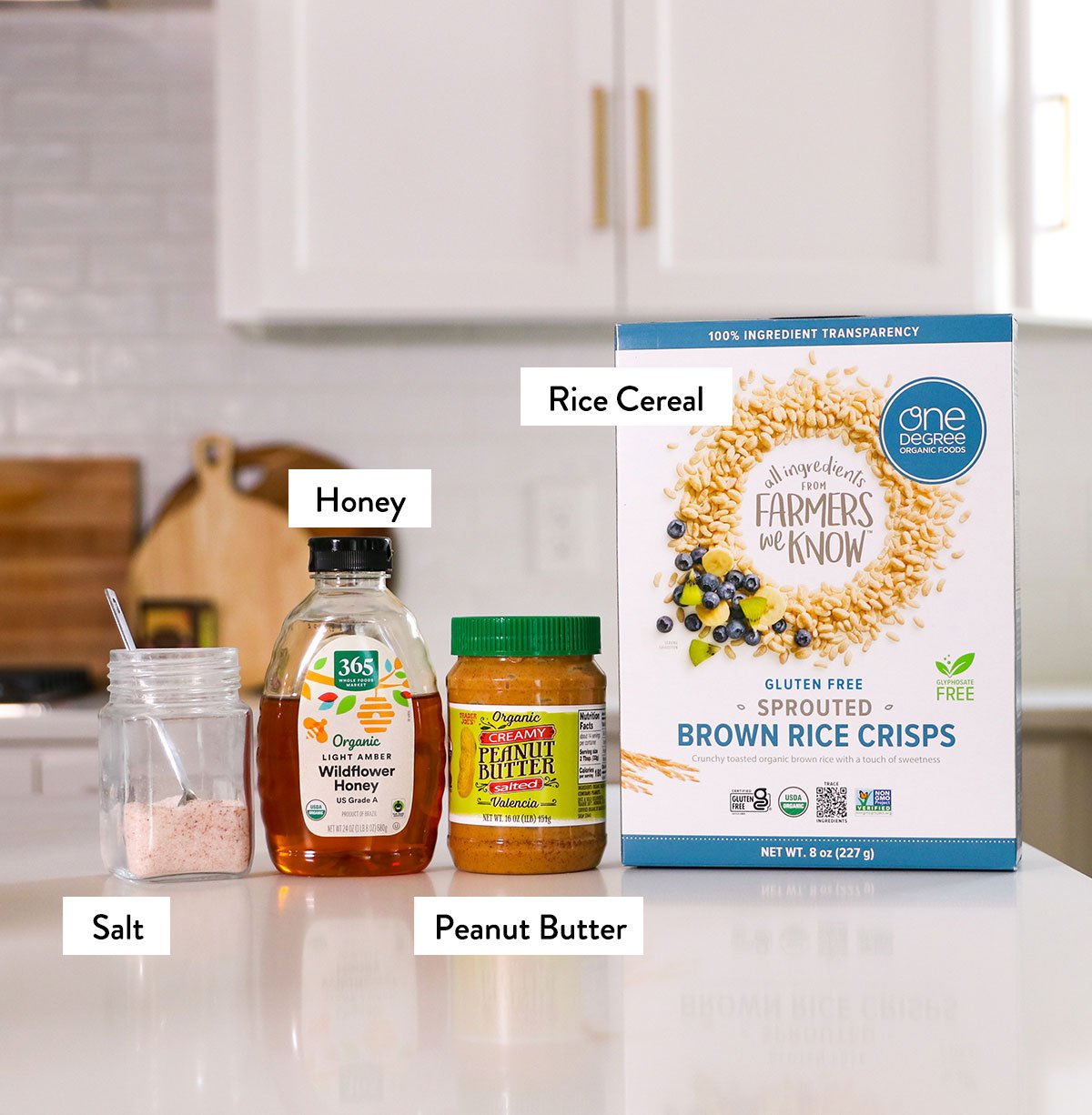 rice cereal, peanut butter, honey, and salt labeled on a white countertop. 