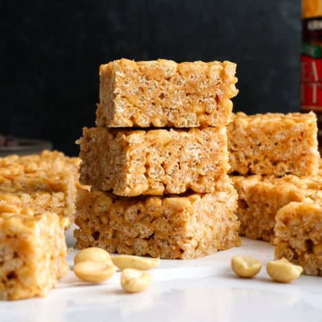 peanut butter rice crispy treats stacked in front of a black background.