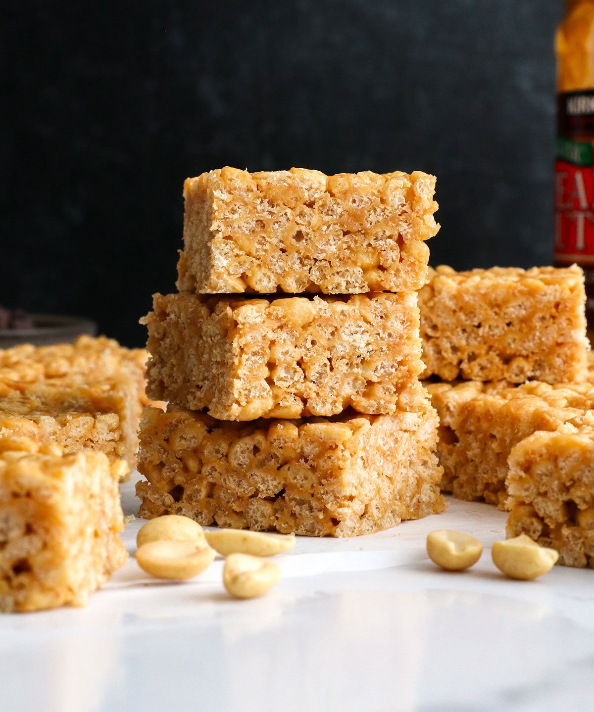 peanut butter rice crispy treats stacked in front of a black background.