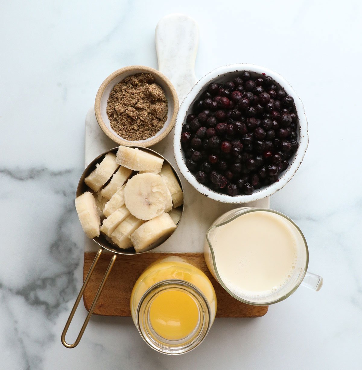 blueberries, banana, flax, oj, and milk on a white board.