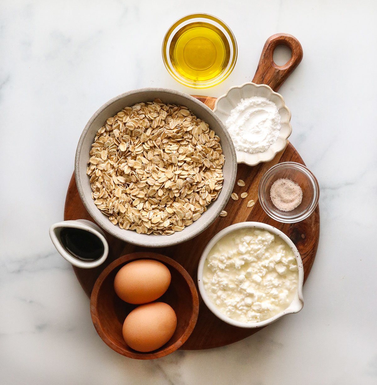 rolled oats, cottage cheese, eggs, olive oil, and maple syrup in separate bowls.