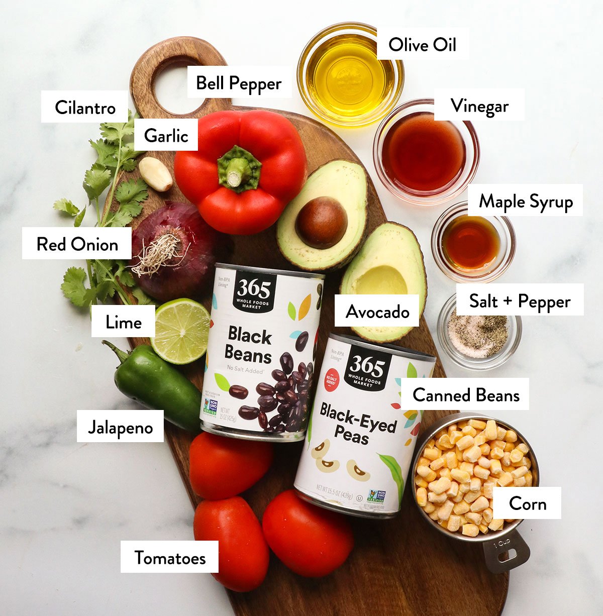 canned beans, bell pepper, onion, cilantro, and dressing ingredients labeled on a white surface. 
