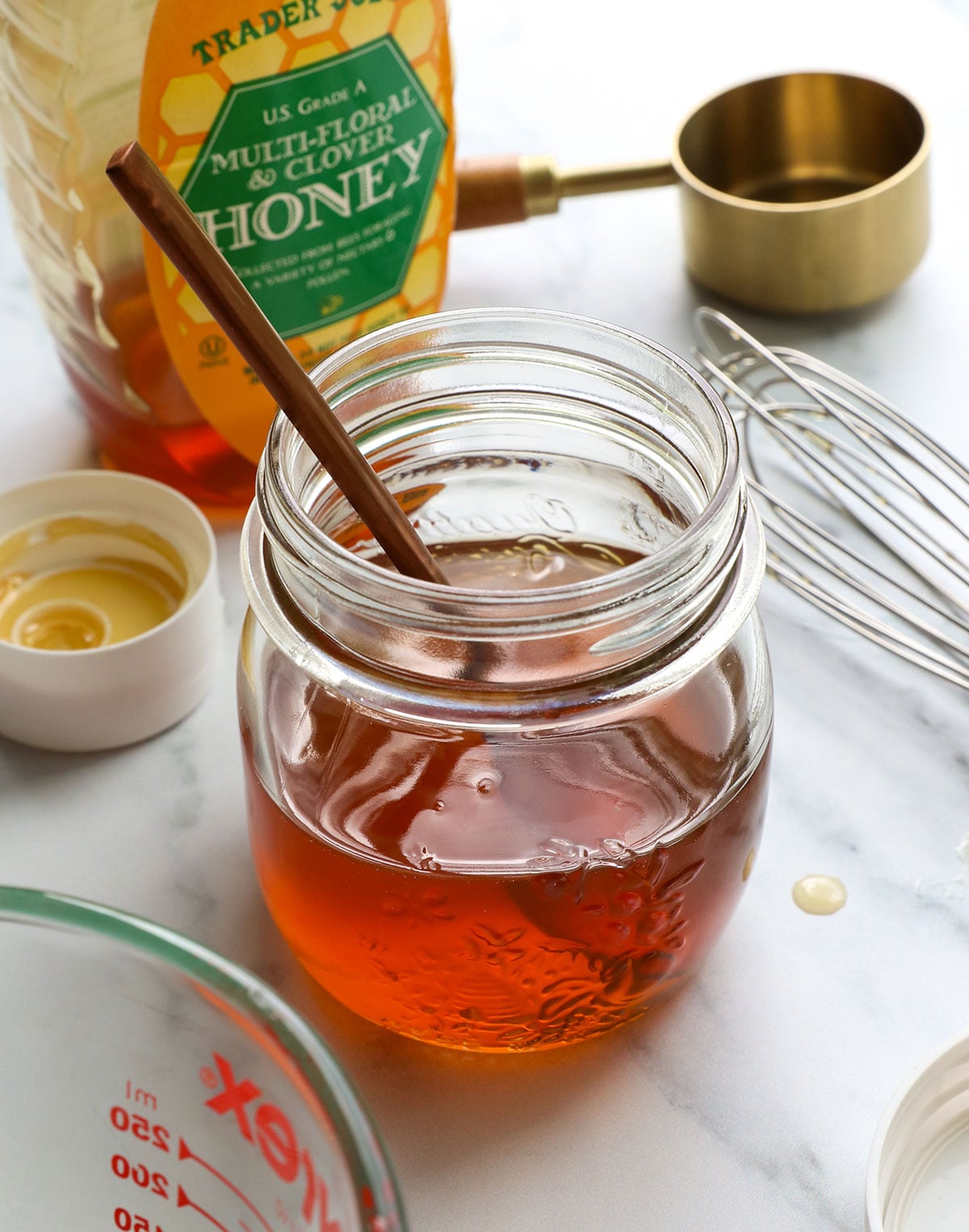 honey simple syrup recipe in a glass jar with a spoon.