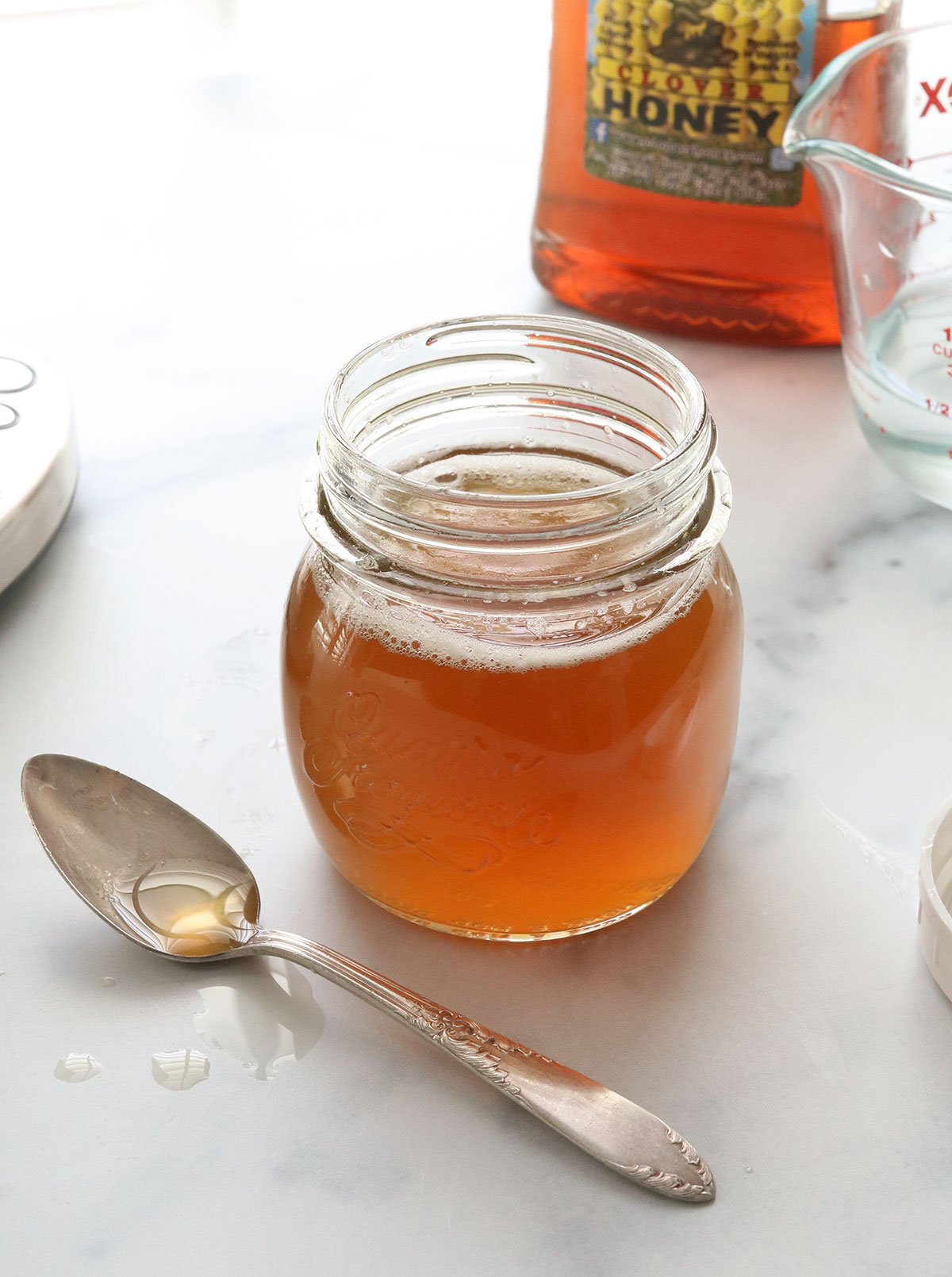 honey simple syrup in a glass jar with a spoon.