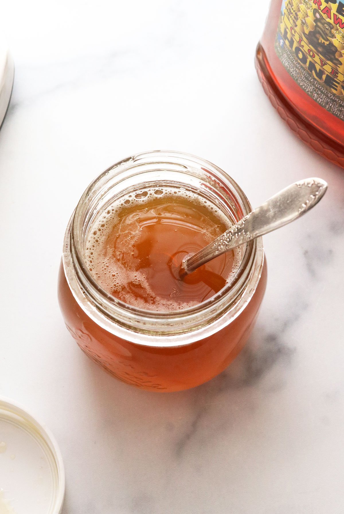 jar of honey simple syrup with a spoon inside.