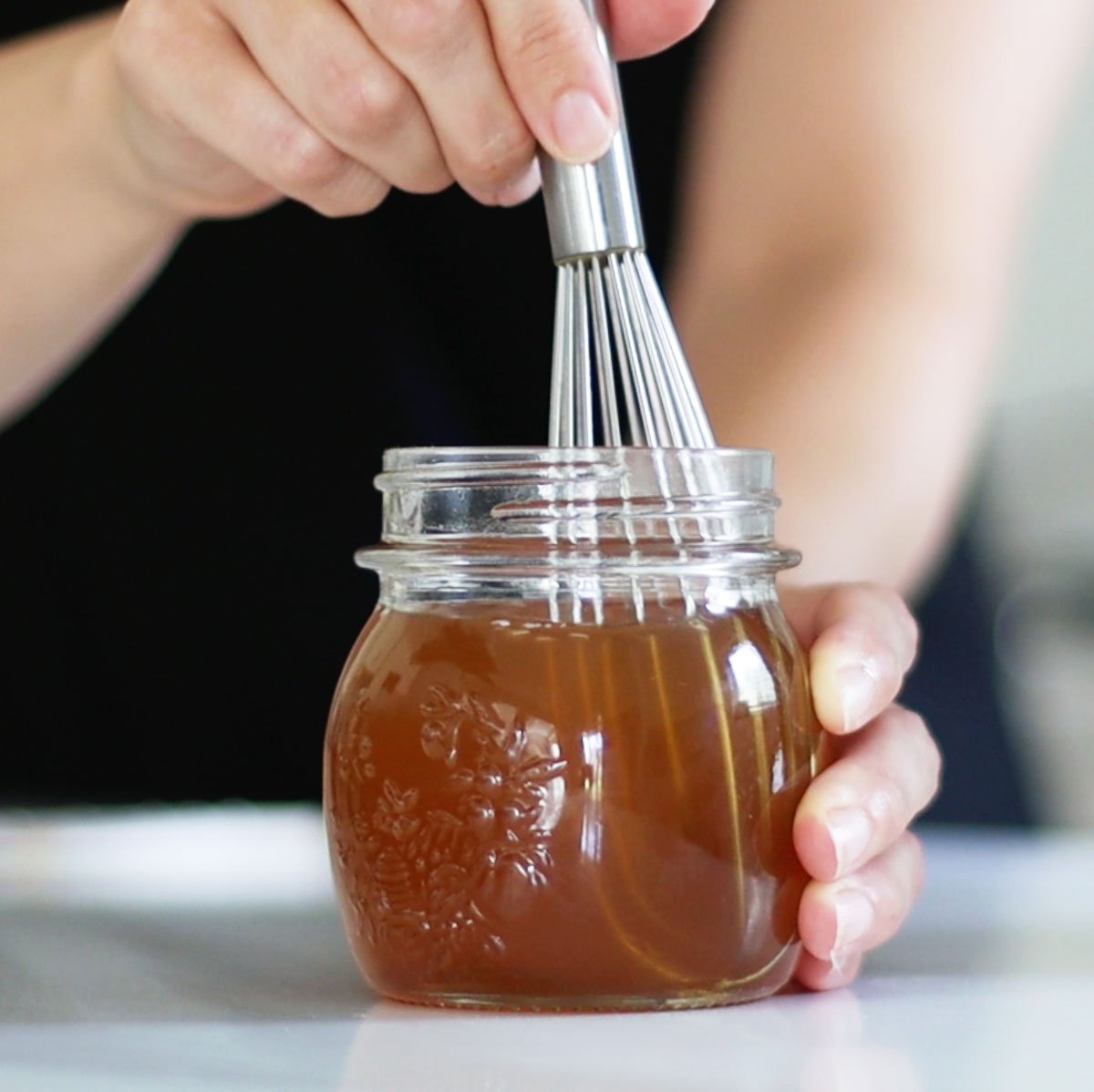 honey simple syrup mixed with a whisk in a jar.