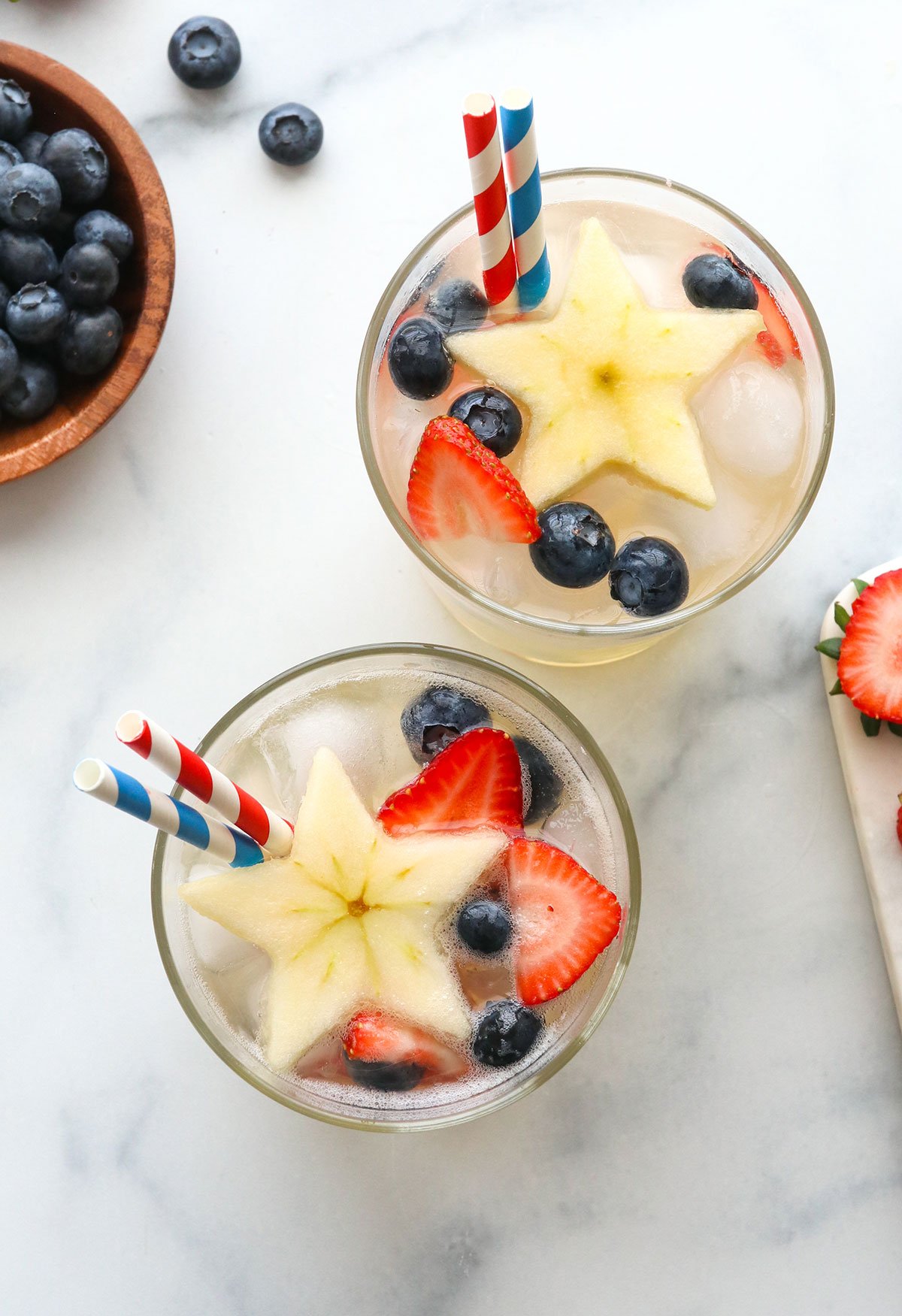 two glasses topped with apple stars and berries.