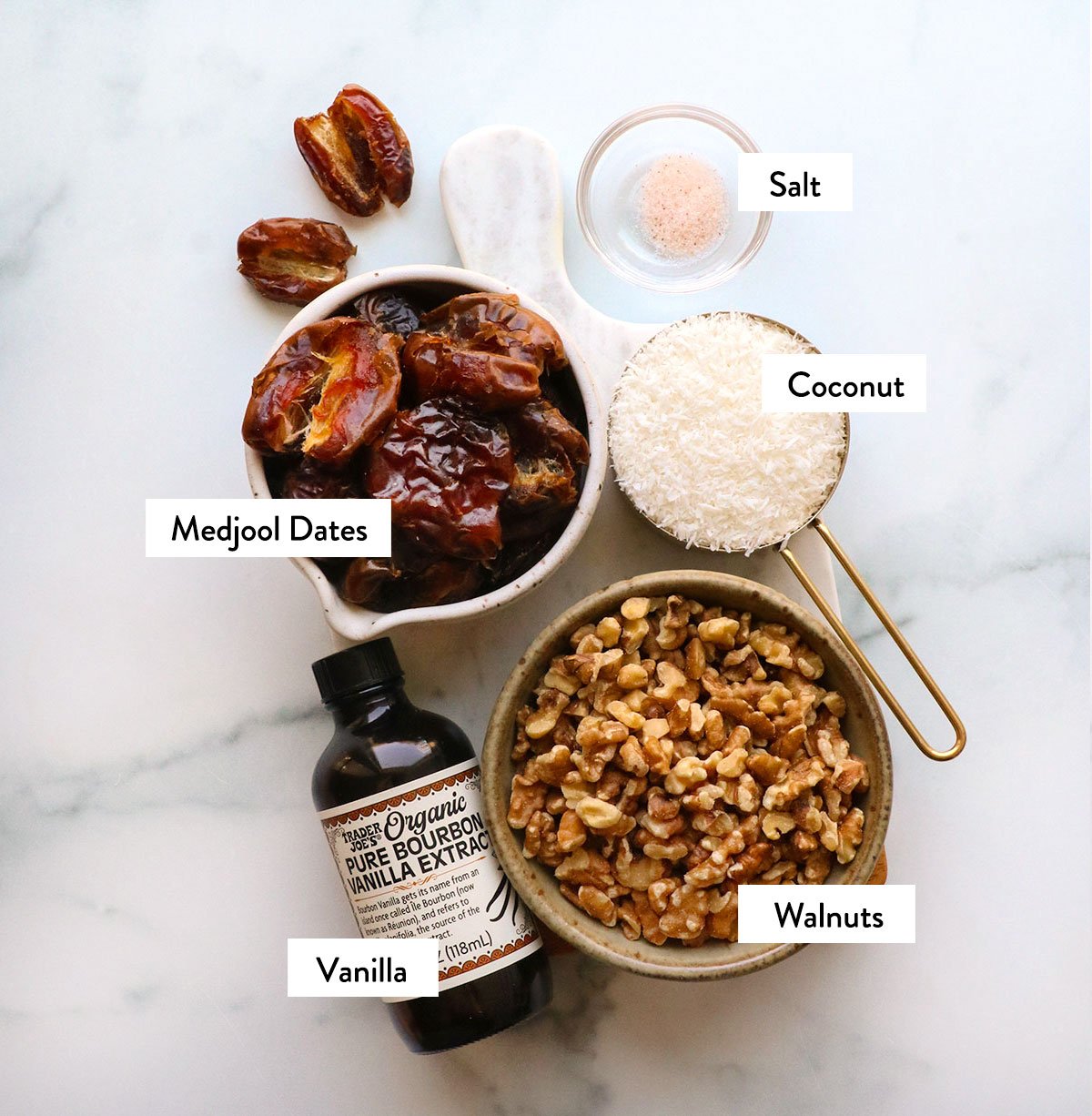 dates, walnuts, coconut, salt, and vanilla extract labeled in bowls. 
