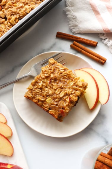 slice of apple baked oatmeal on a white plate with a fork.