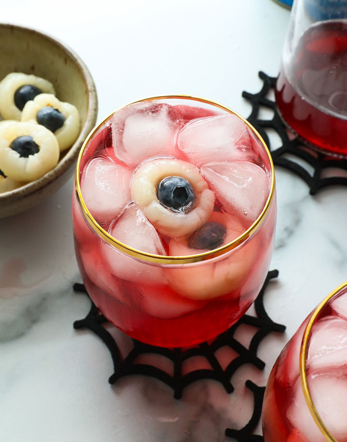 lychee eyeballs floating in a red punch glass with ice.