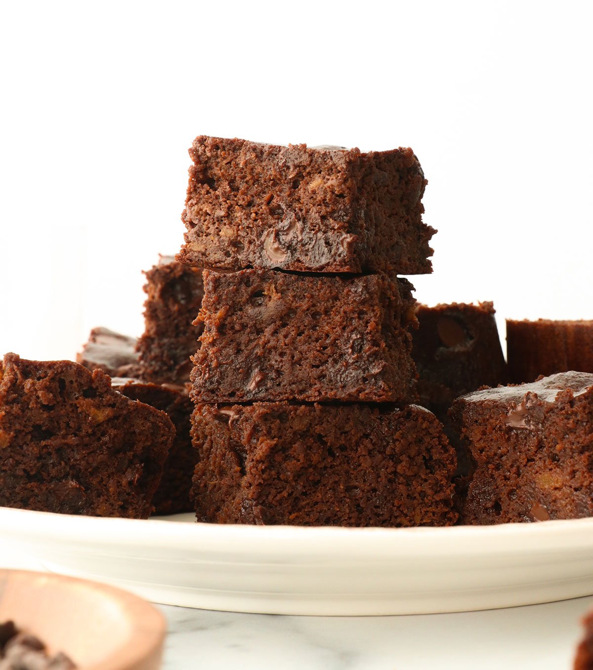 flourless sweet potato brownies stacked on a white plate.