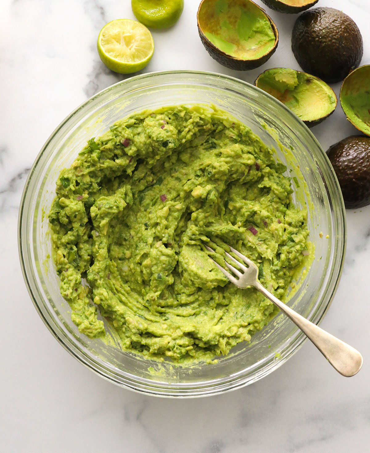 guacamole mashed together in a large glass bowl.