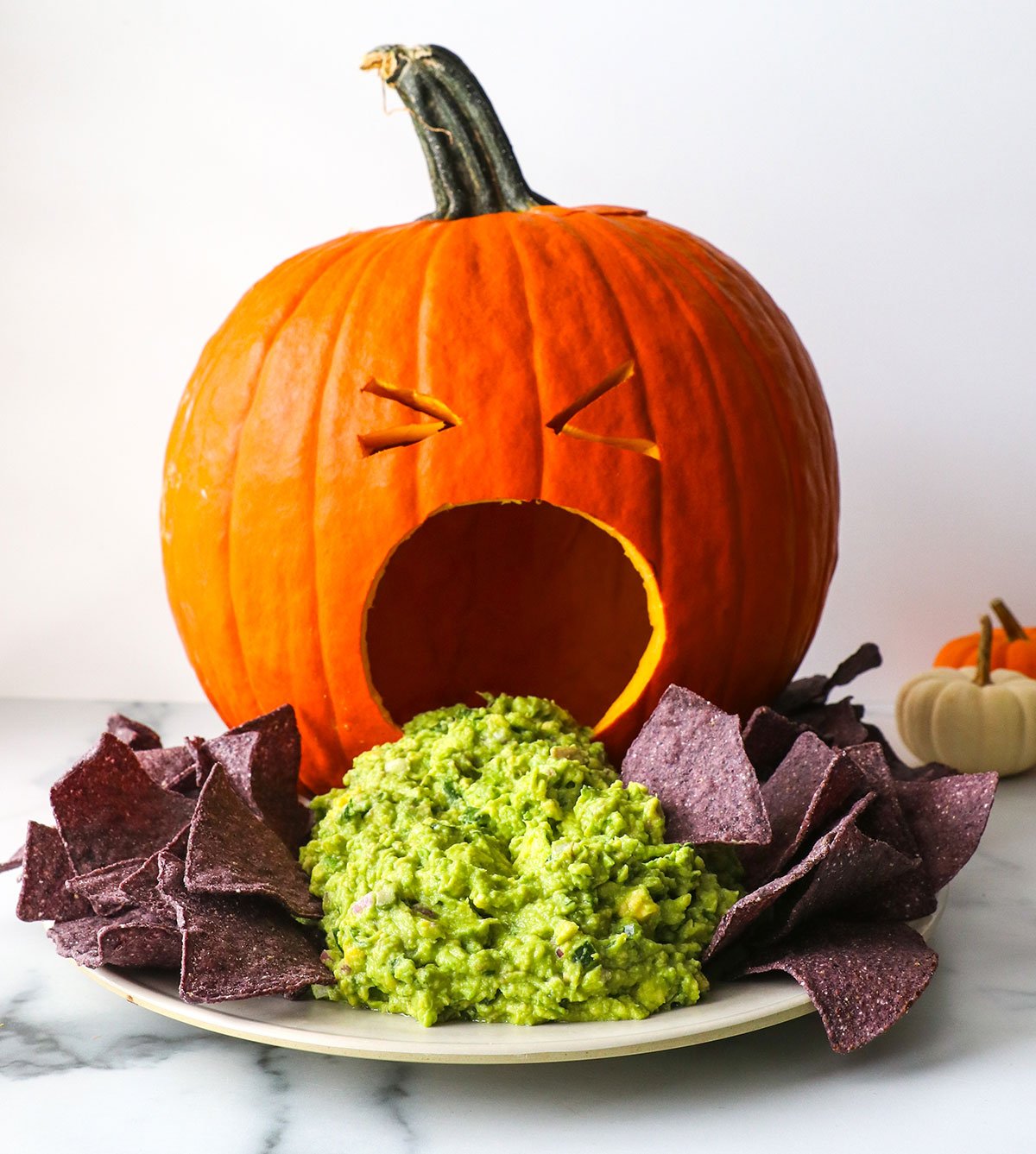 puking pumpkin guacamole appetizer with blue corn tortilla chips