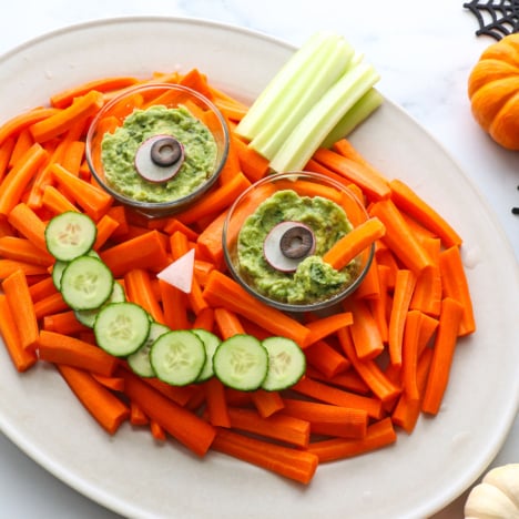 veggies arranged on a platter to look like a pumpkin with eyes and smile.