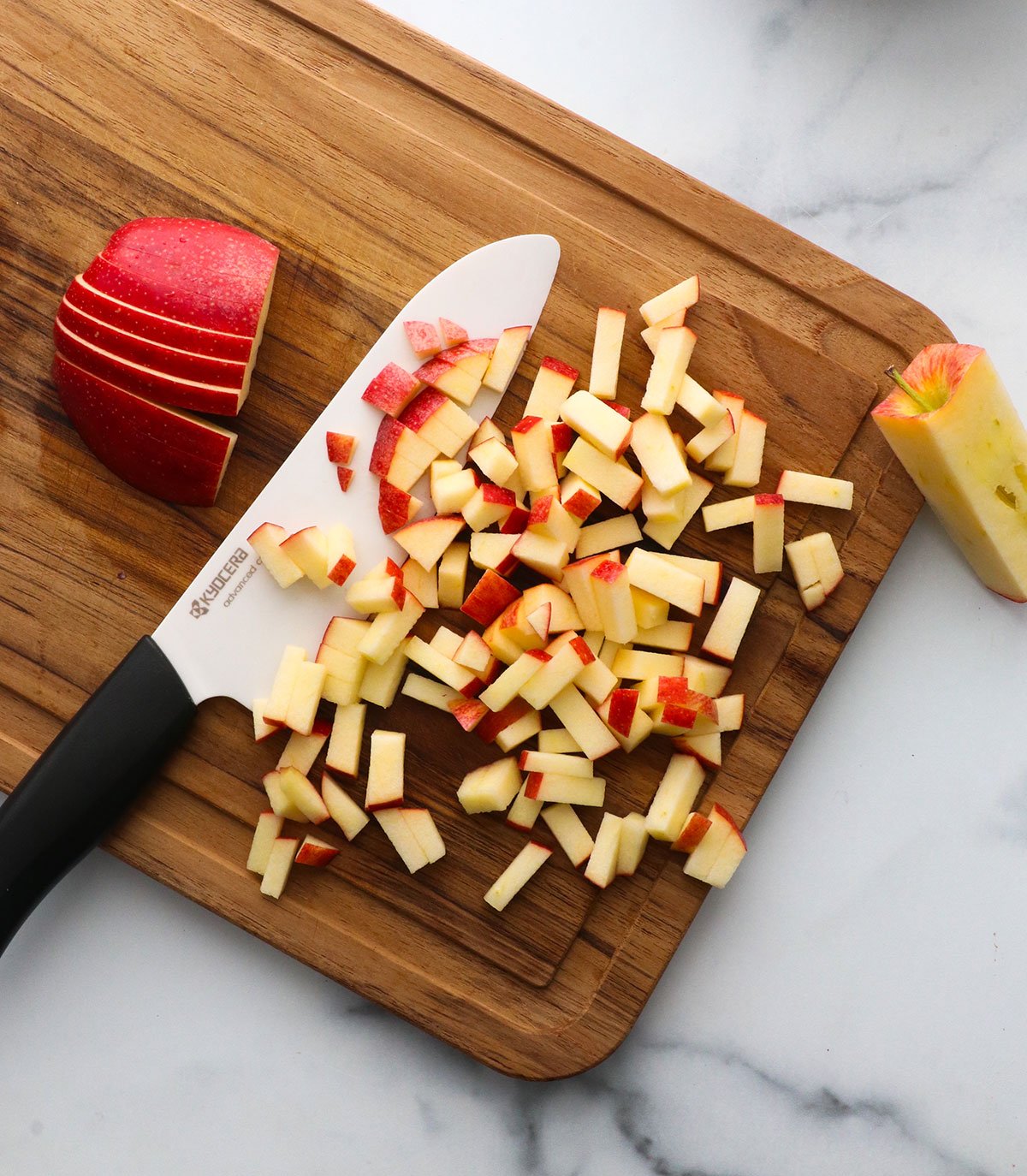 core removed from apple and diced on a cutting board with a ceramic knife.