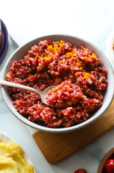 cranberry relish topped with orange zest and served with a spoon.