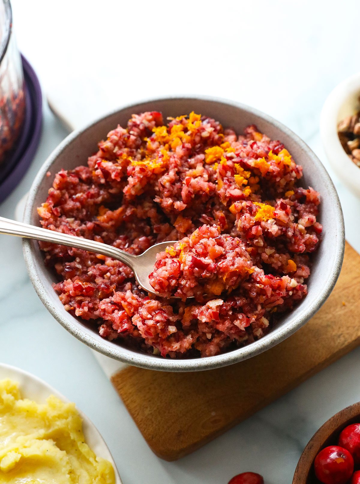 cranberry relish topped with orange zest and served with a spoon.