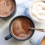 hot chocolate overhead in two blue mugs with whipped cream on the side.