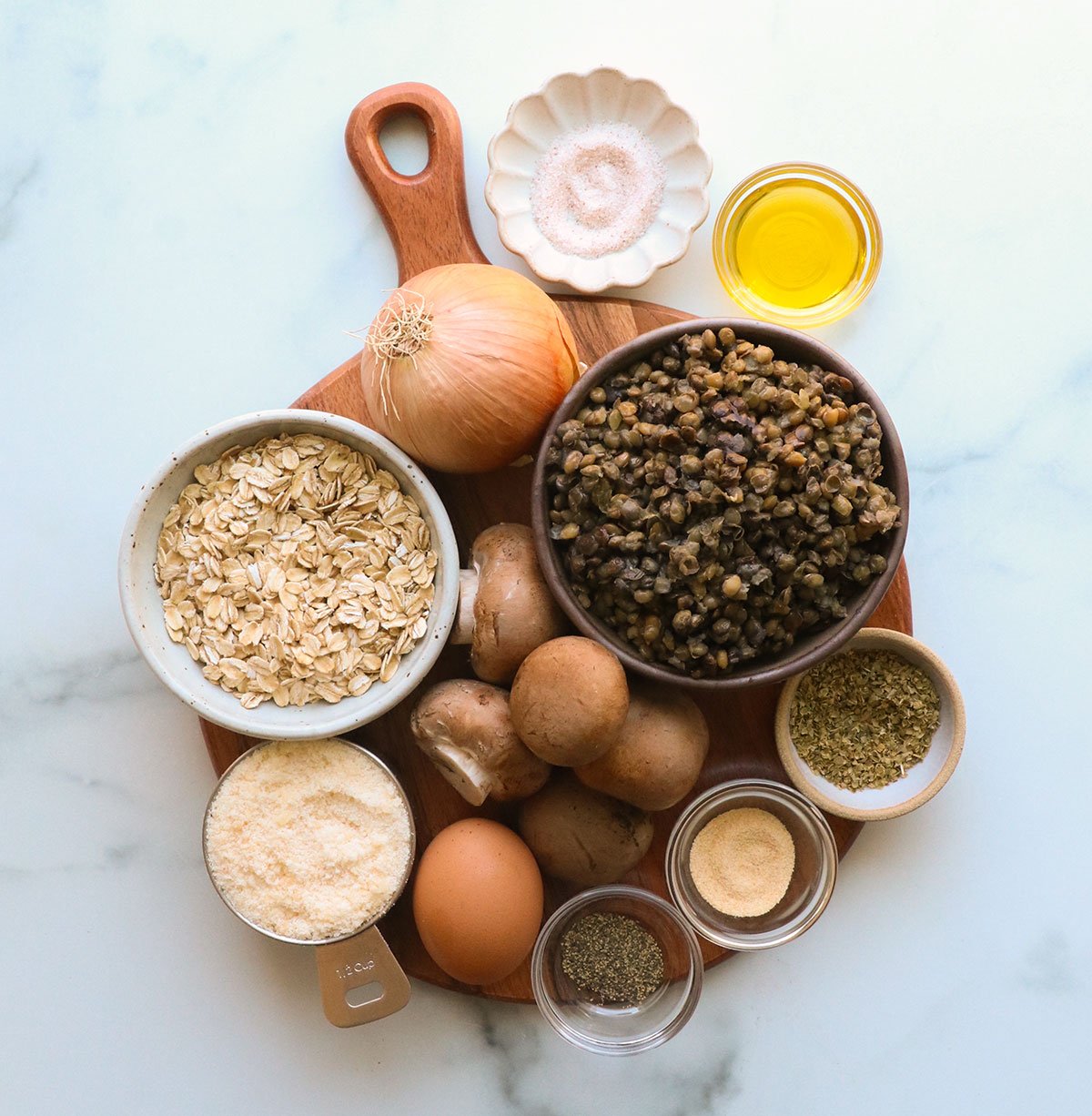 lentils, oats, mushrooms, onions, parmesan, egg, and spices on a wooden board.