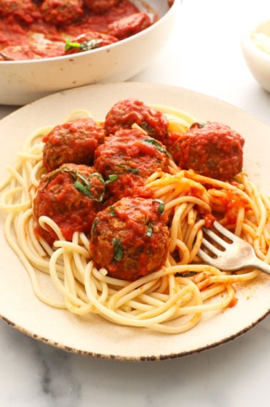 lentil meatballs in marinara sauce on a plate of spaghetti noodles.