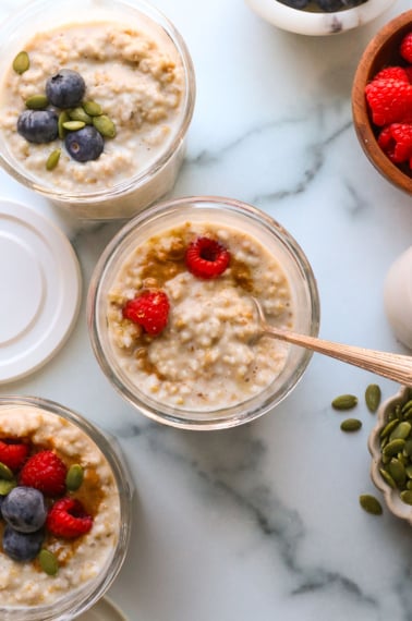 overnight steel cut oats in 3 glass jars topped with berries.